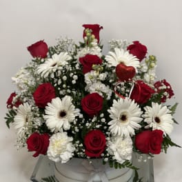 Red roses and white gerbera daisies in a round white box with a red heart pick