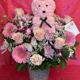 Pink teddy bear in a flower arrangement with roses and gerbera daisies