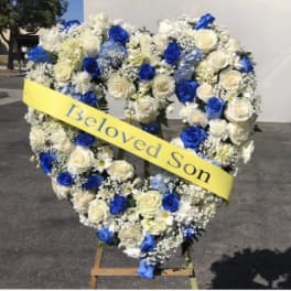 Heart-shaped floral wreath with blue and white roses and a yellow ribbon