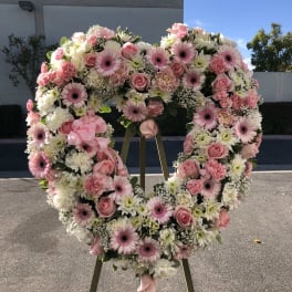 Heart-shaped floral wreath on an easel with pink and white flowers