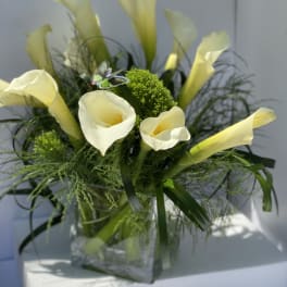 Arrangement of pale yellow calla lilies in a clear glass vase