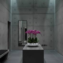 Pink orchids arranged in a white bowl on a pedestal