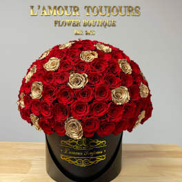 Round bouquet of red and gold roses in a black hatbox