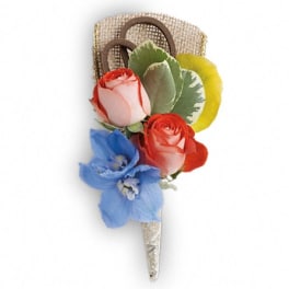 Small floral corsage with roses and a blue flower on a ribbon-wrapped pin
