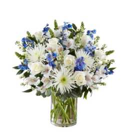 White and blue mixed flower arrangement in a clear glass cylinder vase