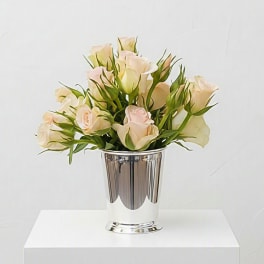 Pale pink and cream roses arranged in a silver vase