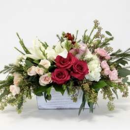 Mixed bouquet in a white wooden box with red, pink, and white flowers