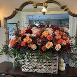 Large basket arrangement of peach, coral, and burgundy roses