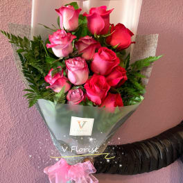 Bouquet of pink and red roses wrapped in clear and gray paper