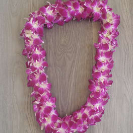 Pink orchid lei on a wood surface