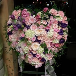 Heart-shaped floral arrangement in pink, white, and purple tones
