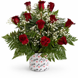 Red roses arranged with white baby's breath in a heart-patterned container