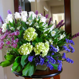 Bouquet of white roses, hydrangeas, and purple flowers in a vase
