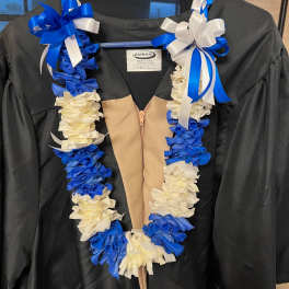 Blue and white lei draped over a black graduation gown