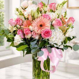 Pink and white mixed bouquet in a glass vase with a pink ribbon