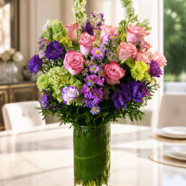 Mixed pink and purple flower arrangement in a tall glass vase