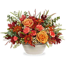 Autumn floral arrangement in a white bowl with orange and pink blooms