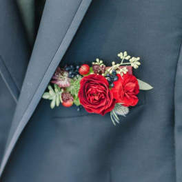 Red floral boutonniere pinned to a dark suit jacket