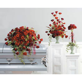 Red rose funeral arrangements displayed on a casket and pedestals