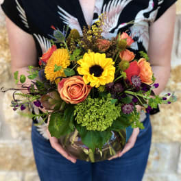 Mixed bouquet of sunflowers, roses, and chrysanthemums in a glass vase
