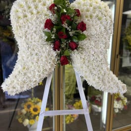 Standing angel wing tribute of white chrysanthemums with red roses on an easel