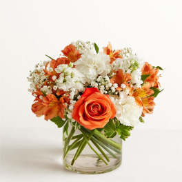 Orange and white flower arrangement in a clear glass vase