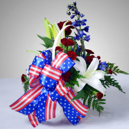 Red, white, and blue floral arrangement with a patriotic ribbon