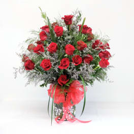 Bouquet of red roses in a glass vase with a red ribbon