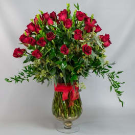 Bouquet of red roses in a clear glass vase with a red ribbon