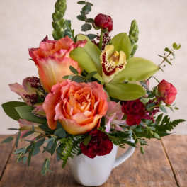 Mixed bouquet in a white mug with peach roses and green orchids