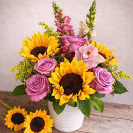Bouquet of sunflowers and lavender roses in a white vase