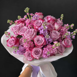 Hand-tied bouquet of pink and lavender roses with small purple filler flowers
