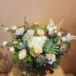 Mixed bouquet with pale roses, white blooms, and a succulent centerpiece