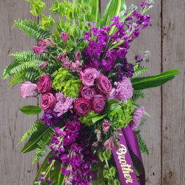 Tall standing floral spray with pink and purple flowers and a ribbon