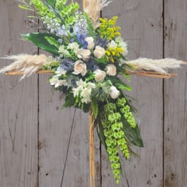 Floral cross arrangement with white roses, green orchids, and pampas grass