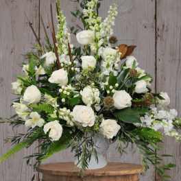 White rose arrangement in a white vase with mixed greenery
