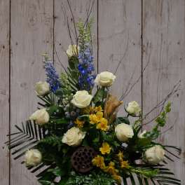 White roses with blue and yellow flowers in a black vase