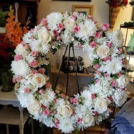Large floral wreath with white and pink roses and white mums on an easel