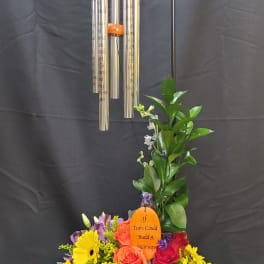 Colorful floral arrangement with wind chimes in a wooden basket