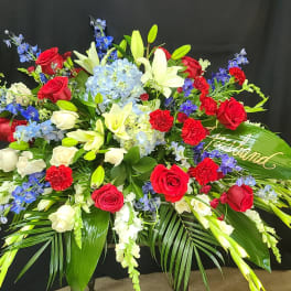 Large floral spray with red and white roses, lilies, and blue flowers