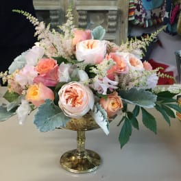 Peach and white roses arranged in a gold pedestal bowl