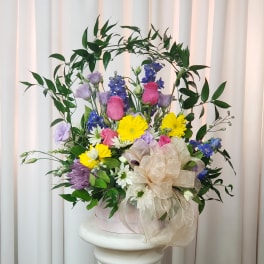 Mixed bouquet with yellow, pink, purple, and white flowers in a pink box