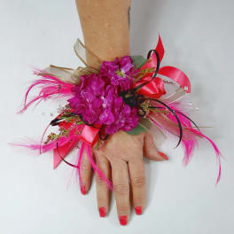 Pink floral wrist corsage with ribbons and feathers
