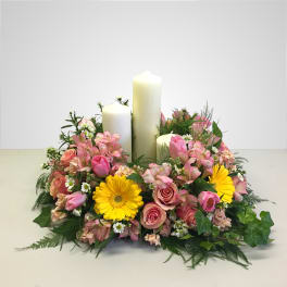 Pink and yellow floral centerpiece with three white pillar candles
