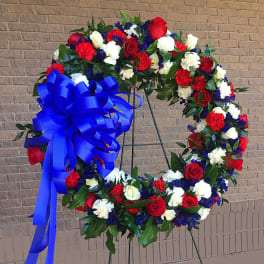 Large red, white, and blue floral wreath with a blue bow on an easel