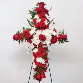 Red and white floral cross arrangement on a stand