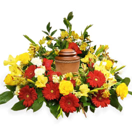 Red and yellow flowers arranged around a wooden urn
