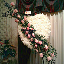 Heart-shaped white floral spray with pink roses on a stand