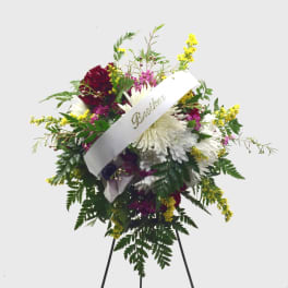 Standing floral spray with white and burgundy flowers and a white ribbon