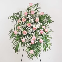 Pink roses and white baby's breath on a standing spray with palm fronds